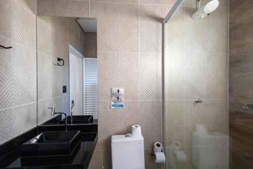 a bathroom with a sink and a toilet and a mirror at Casa Morada Da Praia, Paraiso em Bertioga - Condomínio à beira mar in Bertioga