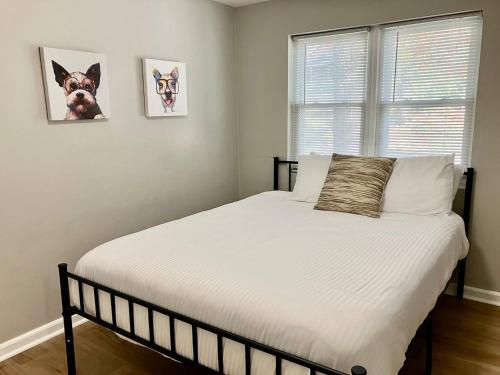 a bedroom with a bed with white sheets and a window at Davenport Dwellings-Two Bedroom Close to UNMC in Omaha