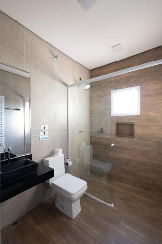 a bathroom with a toilet and a glass shower at Casa Morada Da Praia, Paraiso em Bertioga - Condomínio à beira mar in Bertioga