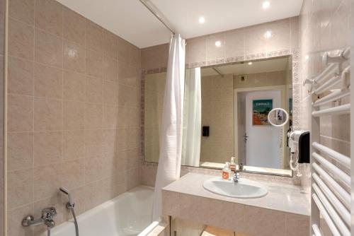 une salle de bain avec une baignoire, un lavabo et un miroir dans l'établissement Le Jardin Secret by Golden Riviera, à Antibes