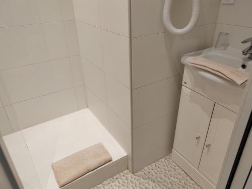 une salle de bain blanche avec une douche et un lavabo dans l'établissement Hôtel Au Grand Duquesne, à Dieppe