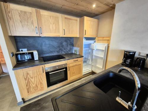 une cuisine avec des armoires en bois et un réfrigérateur dans l'établissement La Residence - Appartement La résidence MAE-9451, à Vénosc