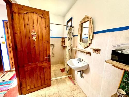a bathroom with a wooden door and a sink at Hippie Chic House in Sidi Kaouki