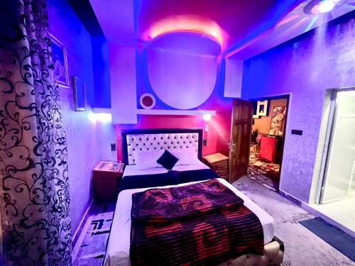 a bedroom with a large bed with purple lighting at Dar Calme Chez El Bouhali in Skoura