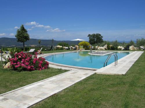 a swimming pool in a yard with pink flowers at Agriturismo Borghetto Il Montino in Rapolano Terme