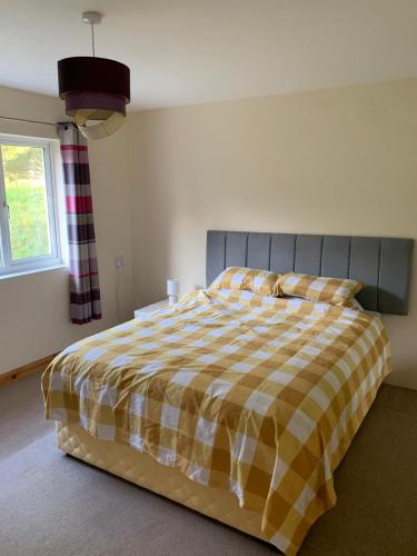 a bedroom with a bed with a checkered blanket at Spacious romantic party cottage with log burner and Ultrafast Fibre near pub Pet friendly in Cross Hands