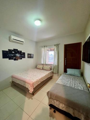 a bedroom with two beds and a window at Casa com piscina, churrasqueira e ar condicionado em condomínio in Cabo Frio