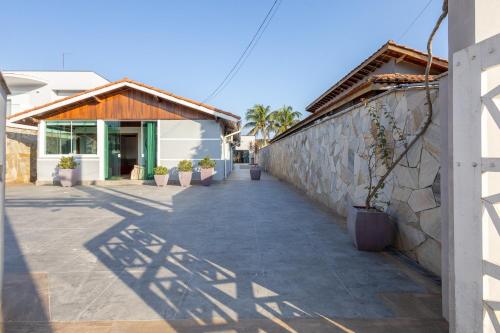 a walkway next to a building with potted plants at Casa Morada Da Praia, Paraiso em Bertioga - Condomínio à beira mar in Bertioga