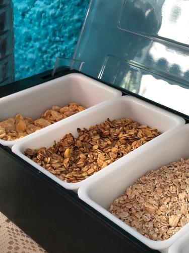 three plastic containers filled with nuts next to a pool at Pousada Turquesa By Gente Bonita in Búzios