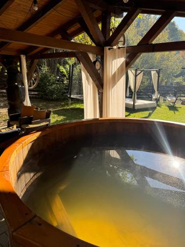 a hot tub in a patio with a wooden roof at Emerald Chalet in Praid