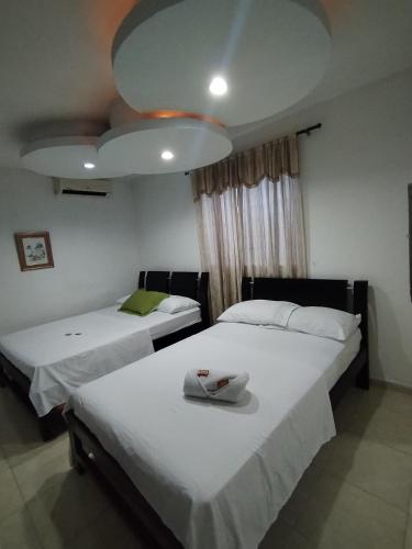 two beds in a hotel room with a hat on them at Hotel La Leyenda Vallenata in Valledupar