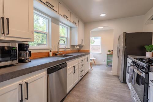 a kitchen with white cabinets and stainless steel appliances at Charming 2BD downtown home by bike trail, river and coffee! in Redding
