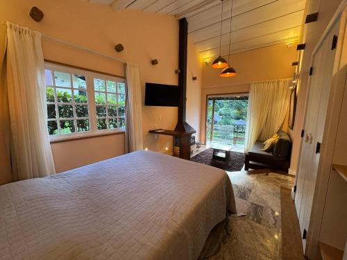 a bedroom with a bed and a chair and windows at Auberge Suisse Pousada in Nova Friburgo