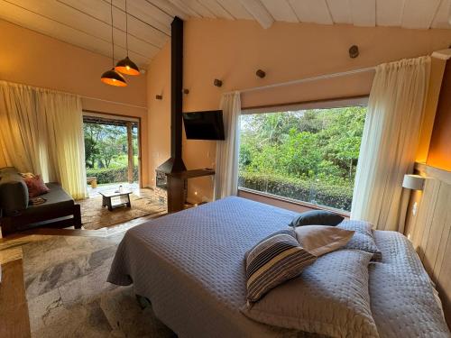 a bedroom with a bed and a large window at Auberge Suisse Pousada in Nova Friburgo