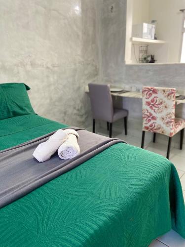 a bedroom with a green bed with two towels at Studio Brownie em Capim Macio in Natal