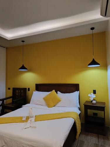 a bedroom with a bed with yellow walls and two lights at Plato De Ciudad II in Boracay