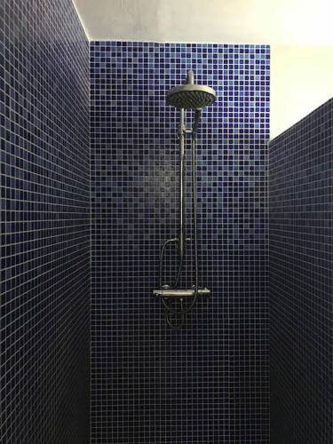 La salle de bains est pourvue de carrelage bleu et d'une douche lumineuse. dans l'établissement Maison pecheur dans le banzeau, à Noirmoutier-en-l'lle