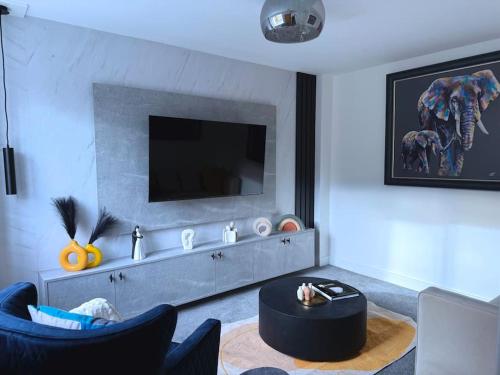 a living room with a tv and a table and chairs at Adeluxe Home - Luxury 2 Bedroom Entire House with Free WiFi, Disney, Netflix and Amazon Prime Included in Burton upon Trent