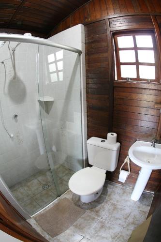 a bathroom with a shower and a toilet and a sink at Chalé Hibisco Amarelo in Juquitiba