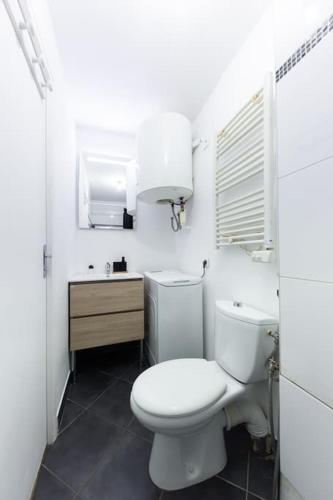 une salle de bain blanche avec des toilettes et un lavabo dans l'établissement T2 Proche de Paris Métro 5, à Pantin