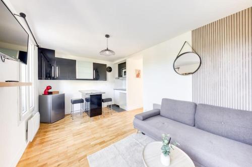 Il comprend un salon avec un canapé gris et une cuisine. dans l'établissement T2 Proche de Paris Métro 5, à Pantin
