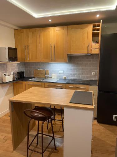 une cuisine avec des armoires en bois et un comptoir avec des tabourets dans l'établissement Appartement au cœur de Paris, à Paris