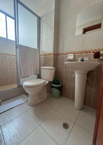 a bathroom with a toilet and a sink at Internacional El Nogal Ipiales in Ipiales