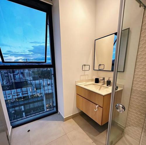 a bathroom with a shower and a sink and a window at Exótico Departamento En La Carolina Edificio QORNER in Quito