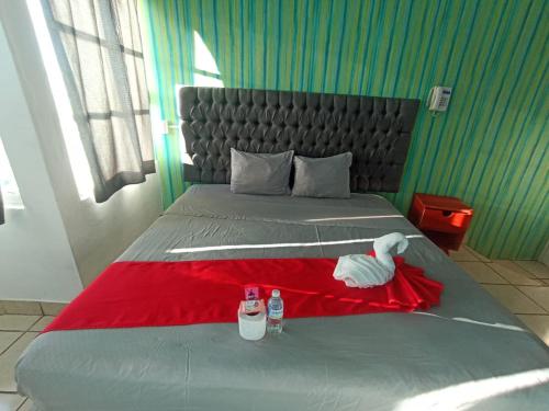 a bed with a red blanket and two bottles on it at Hotel La Intimidad in Antón Lizardo