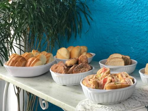 a table topped with bowls of different types of bread at Pousada Turquesa By Gente Bonita in Búzios