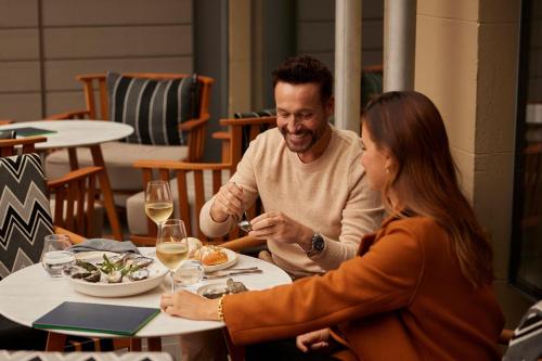 a man and a woman sitting at a table eating food at The Tasman, a Luxury Collection Hotel, Hobart in Hobart