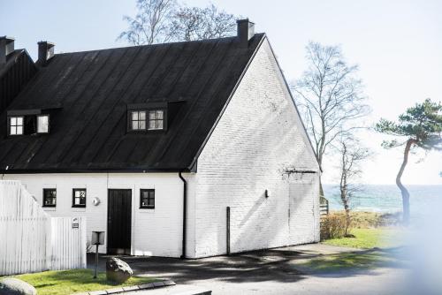 a white house with a black roof at Smygehus Havsbad in Smygehamn