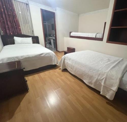 a bedroom with two beds and a wooden floor at Internacional El Nogal Ipiales in Ipiales