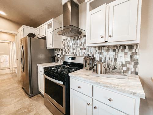 La cuisine est équipée de placards blancs et d'un four avec plaques de cuisson noires. dans l'établissement Beautiful Private Cottage Sunstone, à Reno