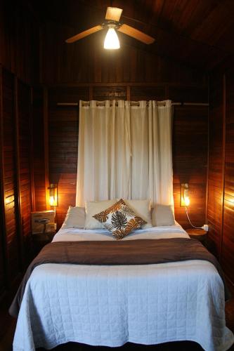 a bedroom with a large bed with a ceiling fan at Chalé Heliconia in Juquitiba