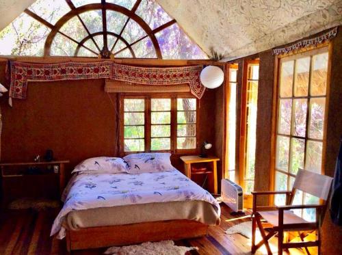 a bedroom with a bed and a large window at La Casa entre los Árboles en el Valle de Elqui Montegrande in Paihuano