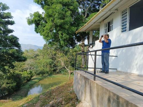 a man standing on a balcony taking a picture of a river at Birding Colombia Lodge cerca a Ibagué in El Real