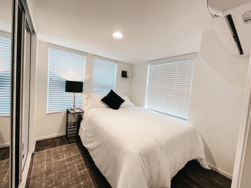 ein Schlafzimmer mit einem Bett mit weißen Laken und Fenstern in der Unterkunft Beautiful Downtown Cottage Onyx in Reno