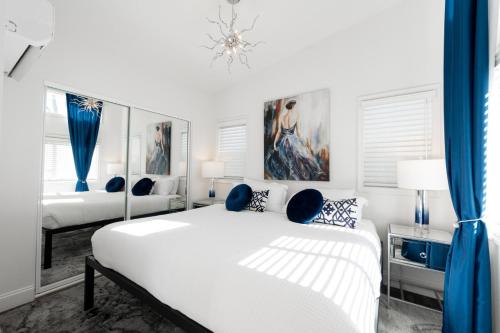 ein weißes Schlafzimmer mit 2 Betten und blauen Vorhängen in der Unterkunft Beautiful Courtyard Cottage Sapphire in Reno