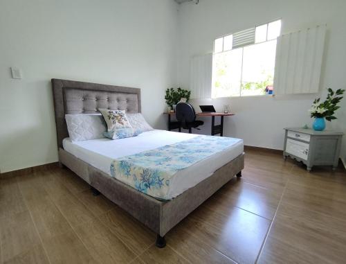 a bedroom with a large bed with a desk and a window at Birding Colombia Lodge cerca a Ibagué in El Real