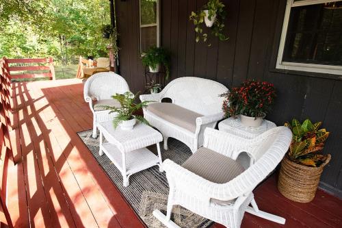 three white wicker chairs and a table on a porch at Osceola Mill in Raphine