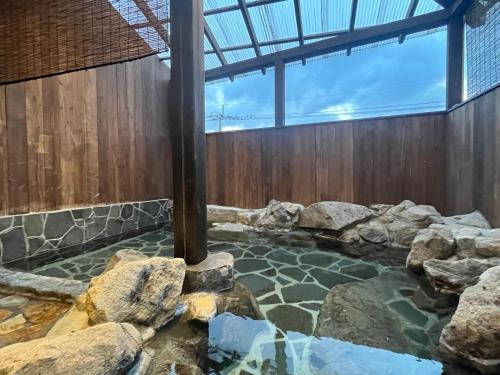 a pool of water with rocks in a building at 湯布院我楽珍民泊Yufuin Garakuchin in Yufuin