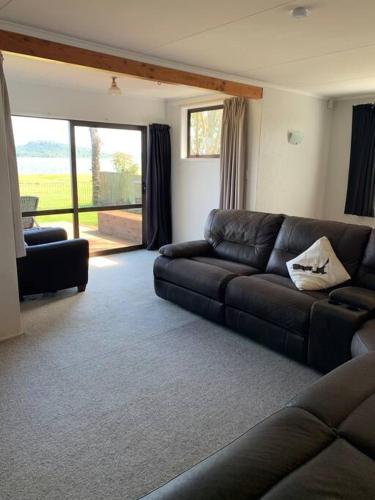 a living room with a leather couch and a sliding glass door at Beautiful Lakefront Location in Rotorua