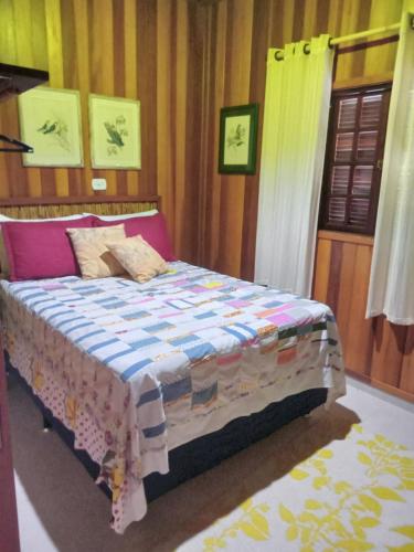 a bedroom with a bed with a colorful blanket on it at Charmosa Cabana Passarim, Gonçalves, Costas in Paraisópolis