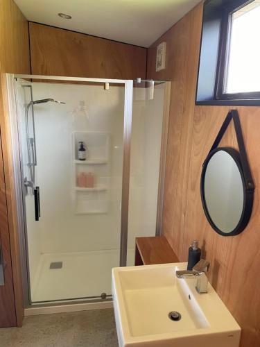 a bathroom with a shower and a sink and a mirror at Studio Shed in The Paddocks in Oakura