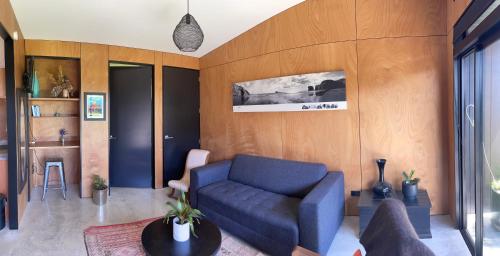 a living room with a blue couch and a table at Studio Shed in The Paddocks in Oakura