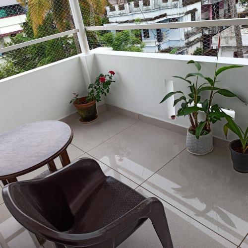 a balcony with a table and a chair and plants at Bethesda Inn in Cochin
