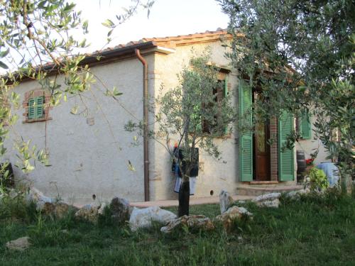a house with green shutters and a tree in front of it at Agriturismo Borghetto Il Montino in Rapolano Terme