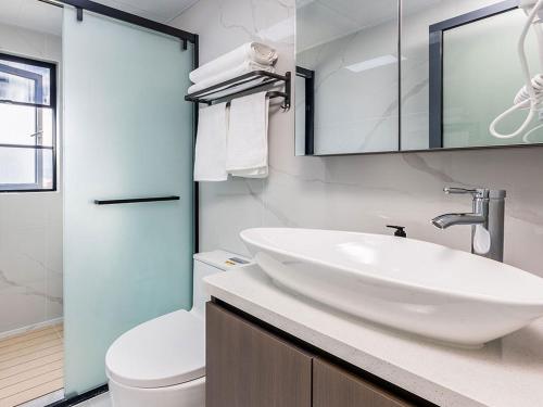 a bathroom with a white sink and a toilet at Annie 2704-only 260 metres from Metro Line 2 Exit C of BeiChun in Kunming