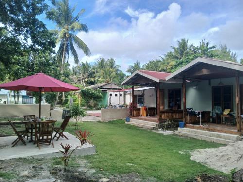 a house with a yard with a table and an umbrella at Renata Cottages in Ohoililir